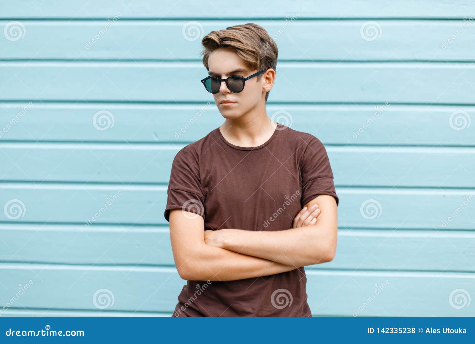 Hombre Joven Elegante Del Inconformista Con Un Peinado Moda En Gafas De Sol Oscuras En Una Camiseta Marrón De Moda Que Present Foto de archivo - Imagen de camisa, hombres: 142335238