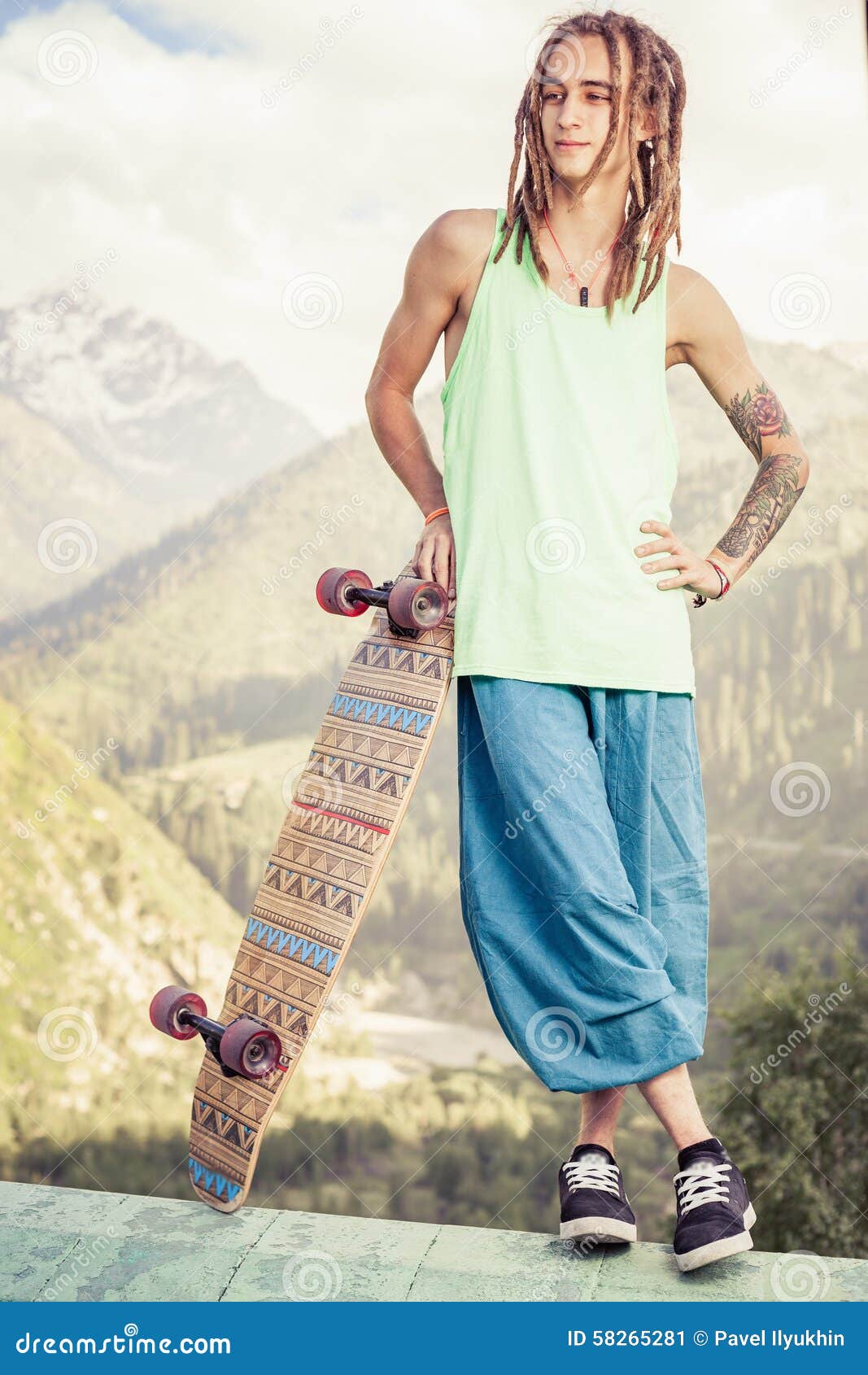Hombre joven y hermoso del hippie con el monopatín del longboard en la montaña. Hombre joven y hermoso del hippie con el monopatín al aire libre en la montaña Longboard es la cultura joven más popular y más peligrosa