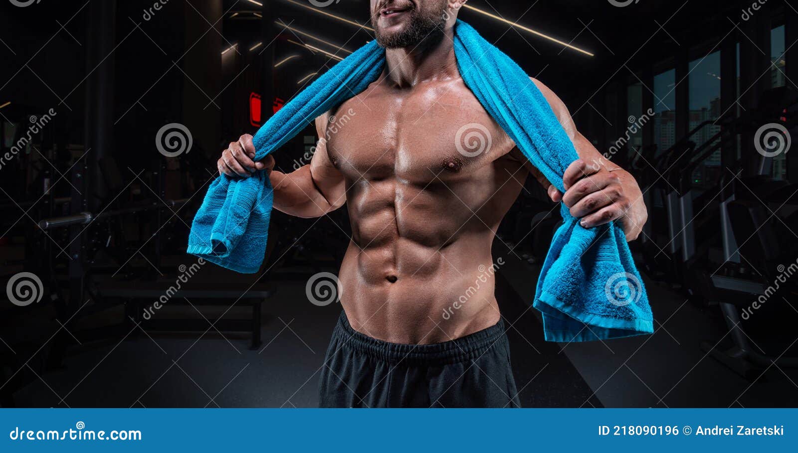 Hombre musculoso posando en el gimnasio con una toalla sobre los hombros.  concepto de fitness.