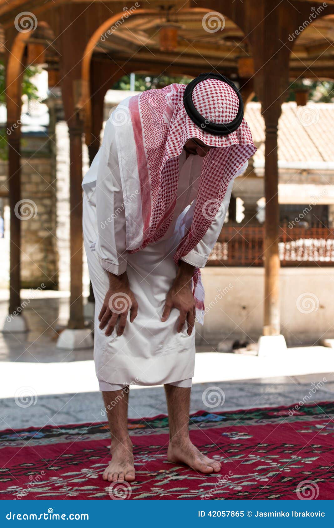 Hombre musulmán joven que ruega. Hombre musulmán joven que hace rezo tradicional a dios mientras que lleva un casquillo tradicional Dishdasha