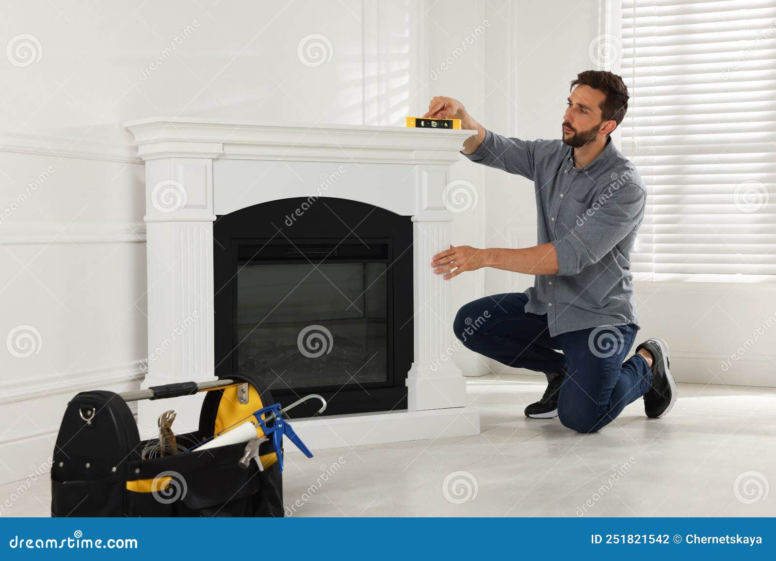 Hombre Que Utiliza El Nivel De Construcción Para Instalar La Chimenea  Eléctrica Cerca De La Pared Blanca De La Habitación Foto de archivo -  Imagen de sitio, hombre: 251821542