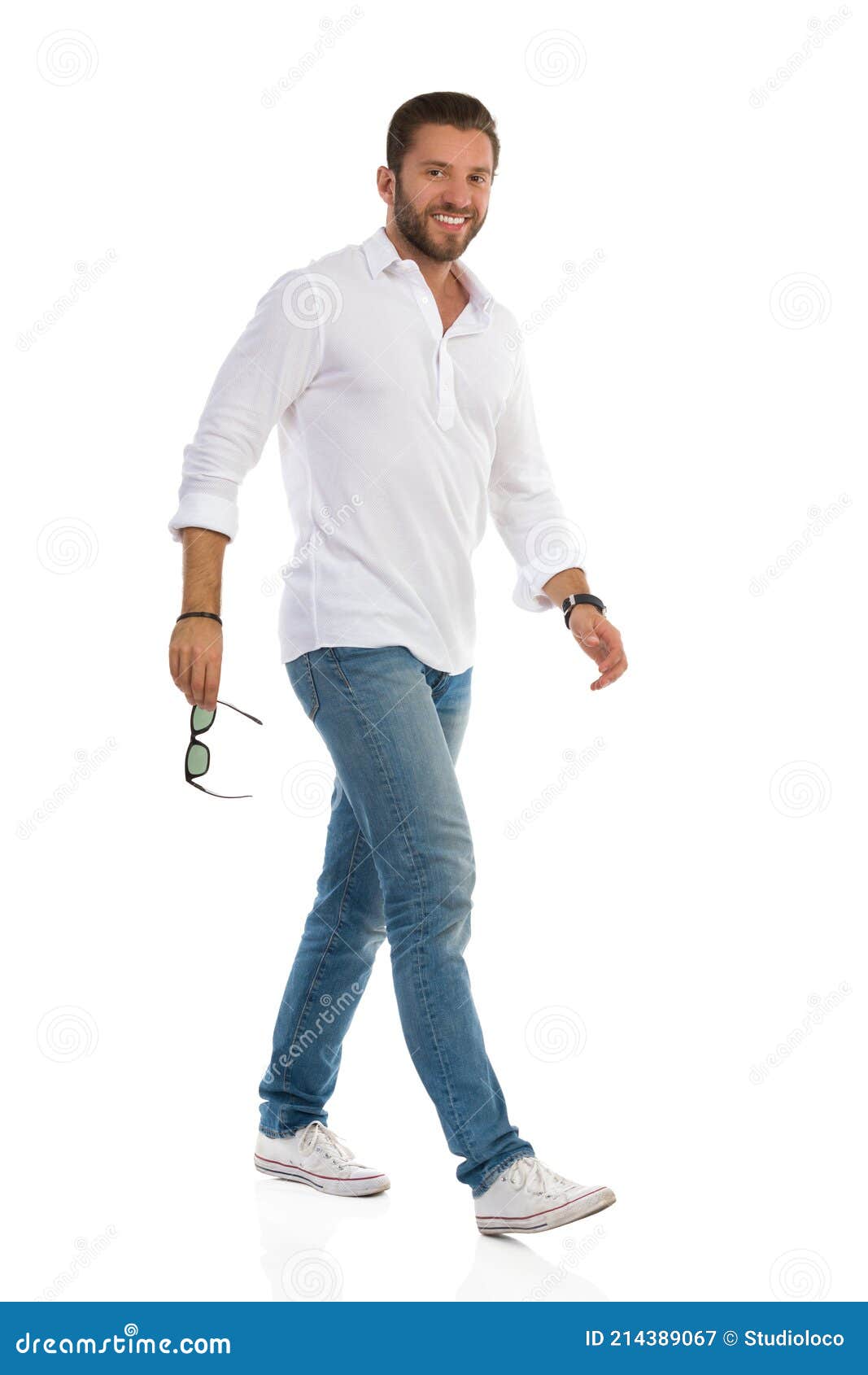 Hombre Sonriente De Camisa Blanca Jeans Y Zapatillas De Deporte Caminar Y Mirar a Cámara. Vista Lateral Imagen de archivo - Imagen de marcha, vaqueros: 214389067