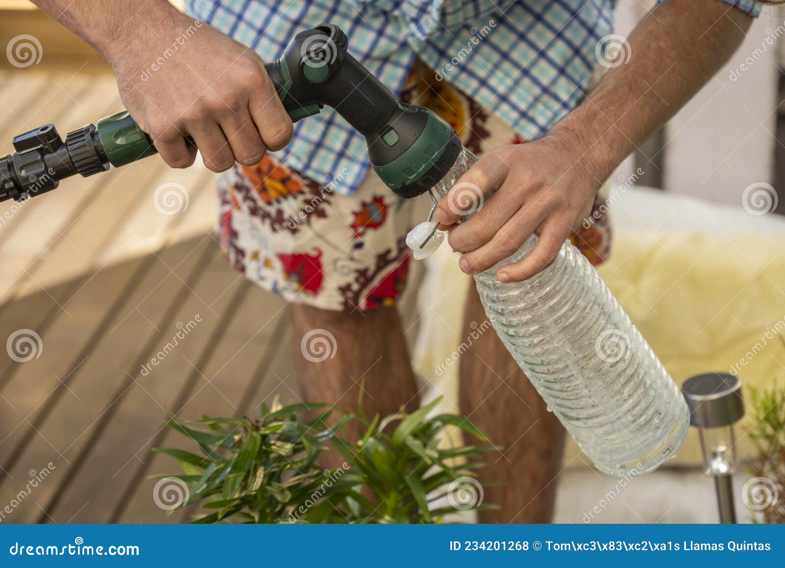 man wearing a plaid shirt filling a water bottle to water plants