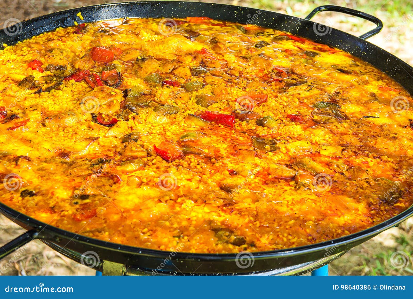 home cooked spanish valencian paella in large flat frying pan. variety of meats, vegetables, rice, tomato sauce.