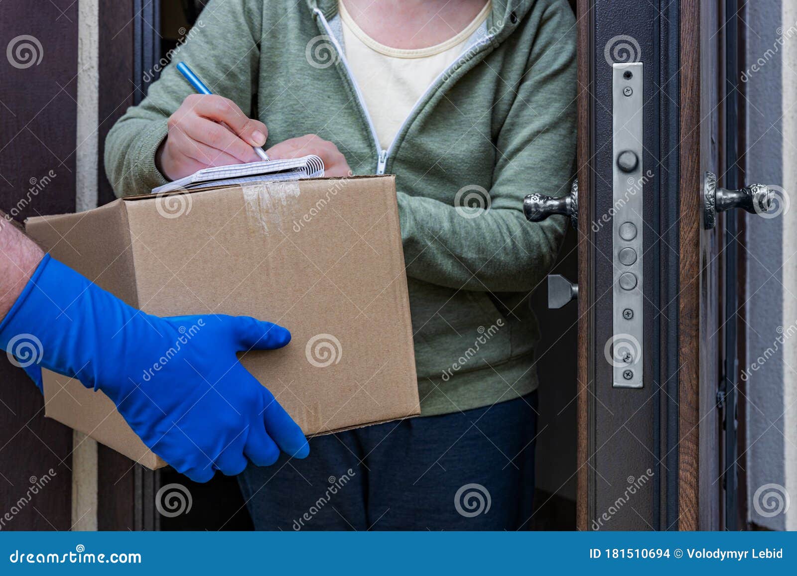 home delivery, a courier in gloves in front of the open door of the house passes the parcel to the woman who signs for