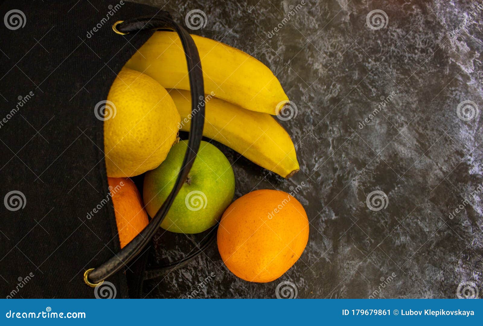 home delivery of products.helping people during a pandemic.banana, lemon, apple, tangerines in a black bag lie on a dark table