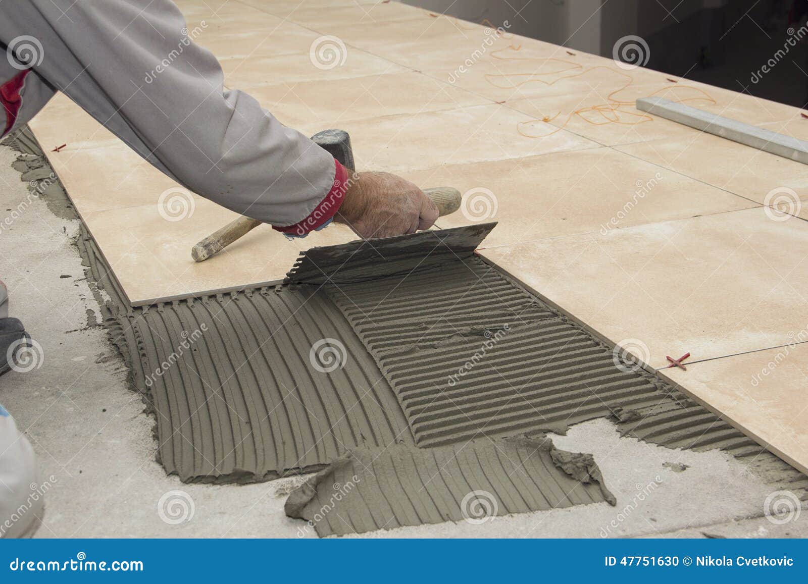 home improvement, renovation - construction worker tiler is tiling, ceramic tile floor adhesive, trowel with mortar