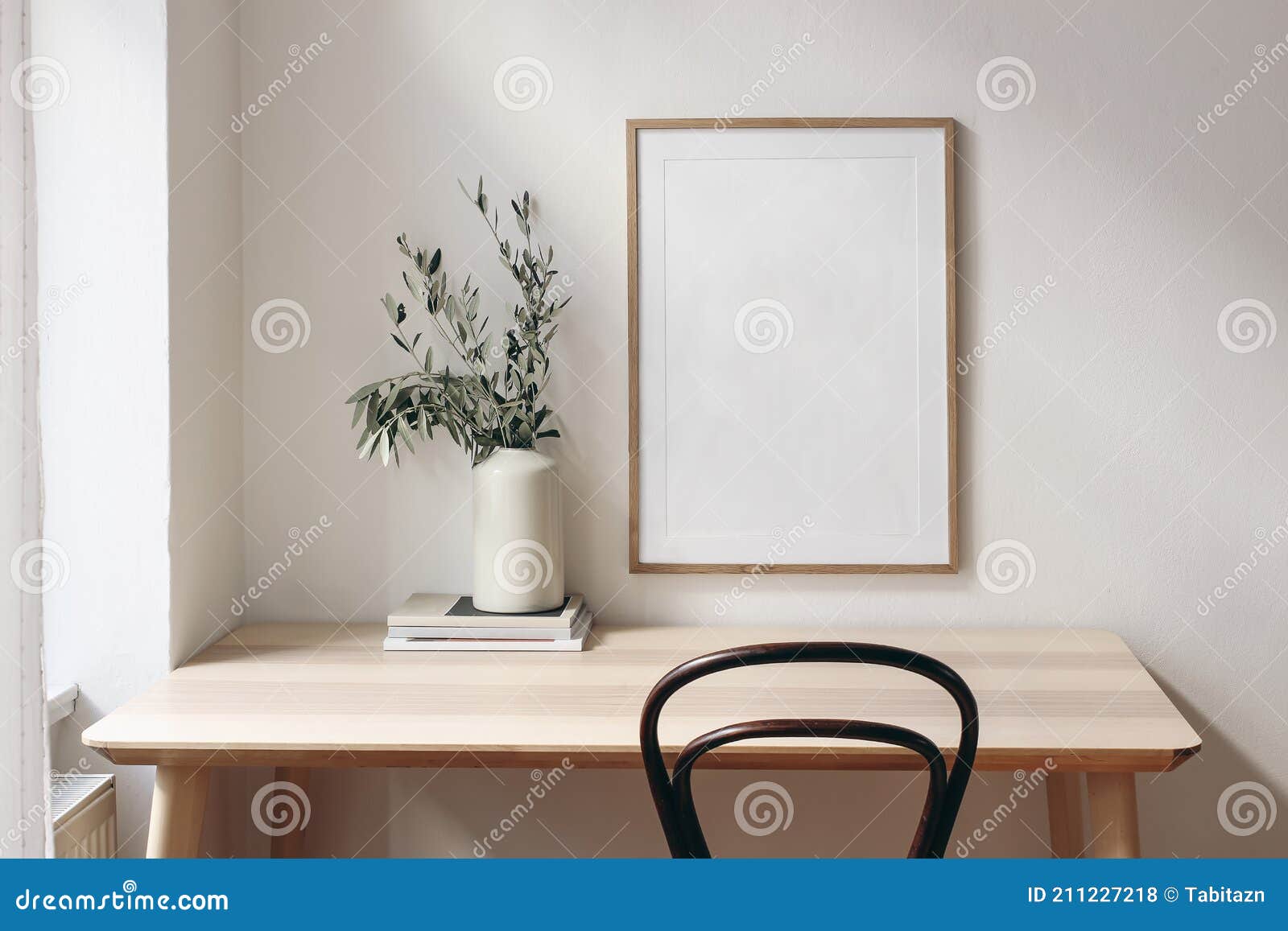 home office concept. old books, empty vertical wooden picture frame mockup hanging on white wall. wooden desk, table