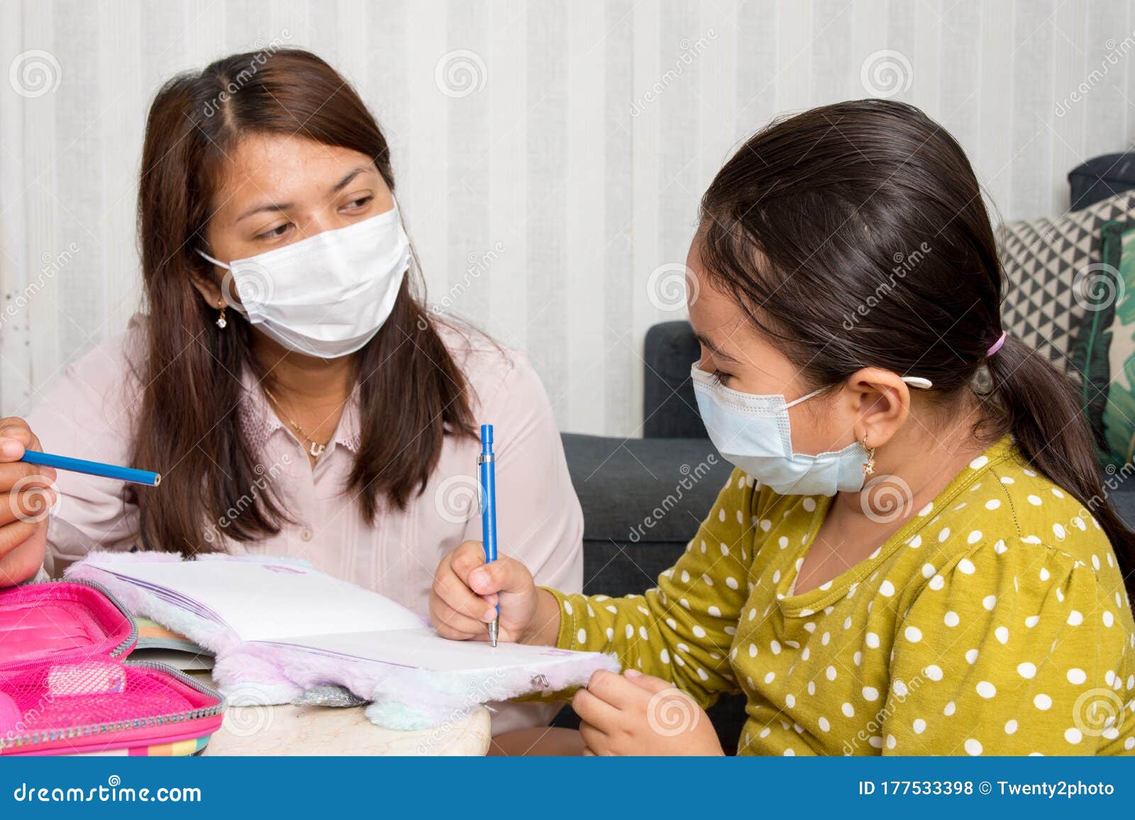 home schooling concept image with mother and daughter studying while wearing face masks because of current corona virus threat