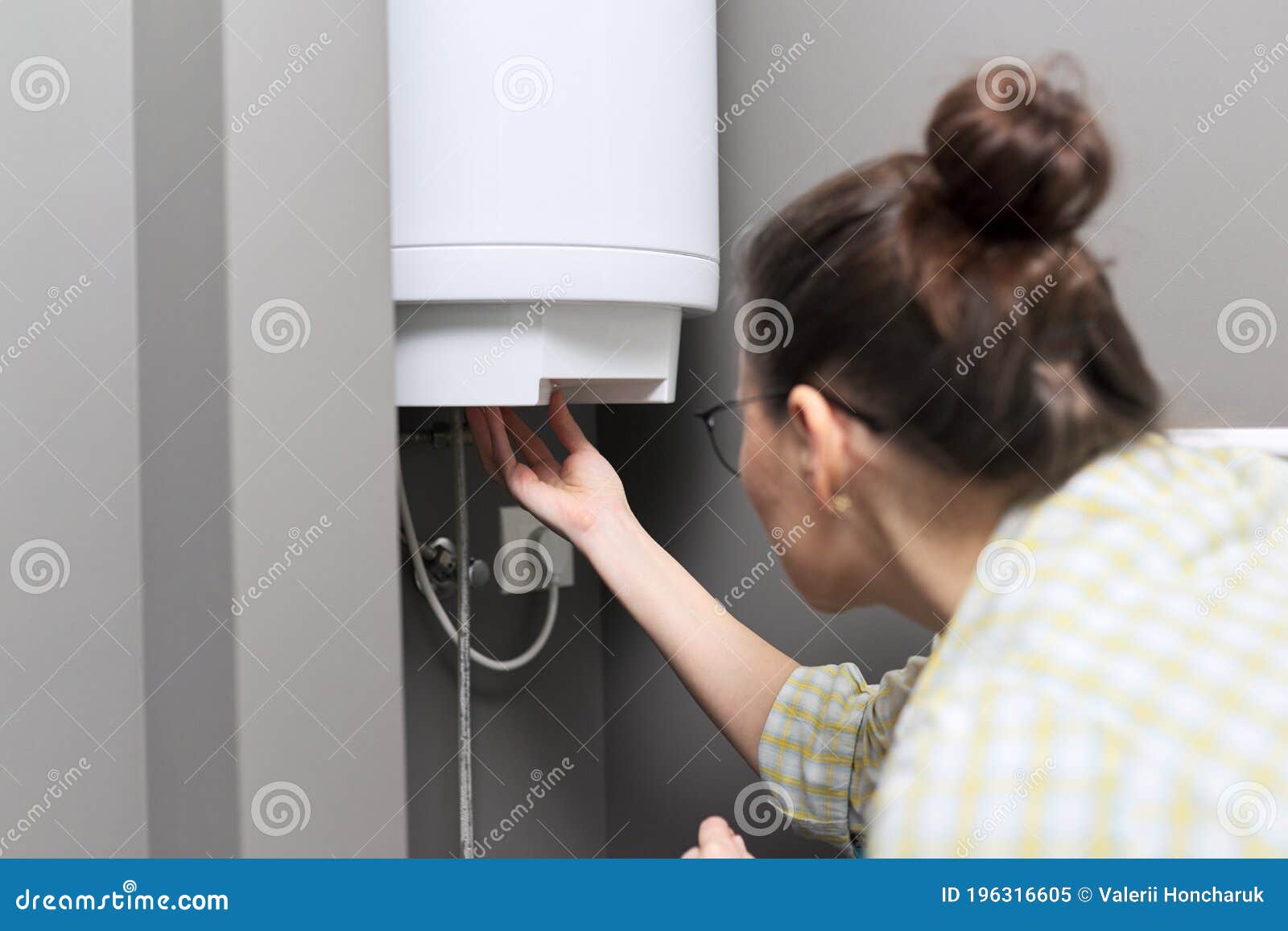 home water heater, woman regulates the temperature on an electric water heater