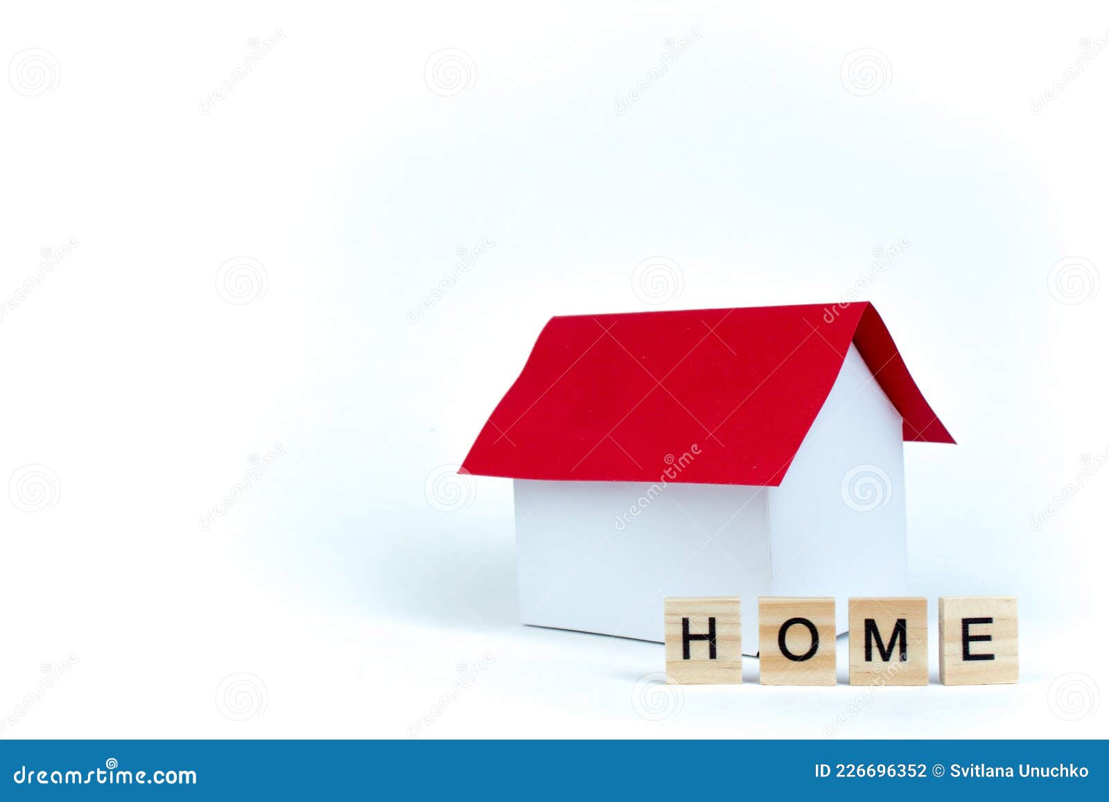 home- word composed fromwooden blocks letters on red background, layout of a house with a red roof. copy space for ad