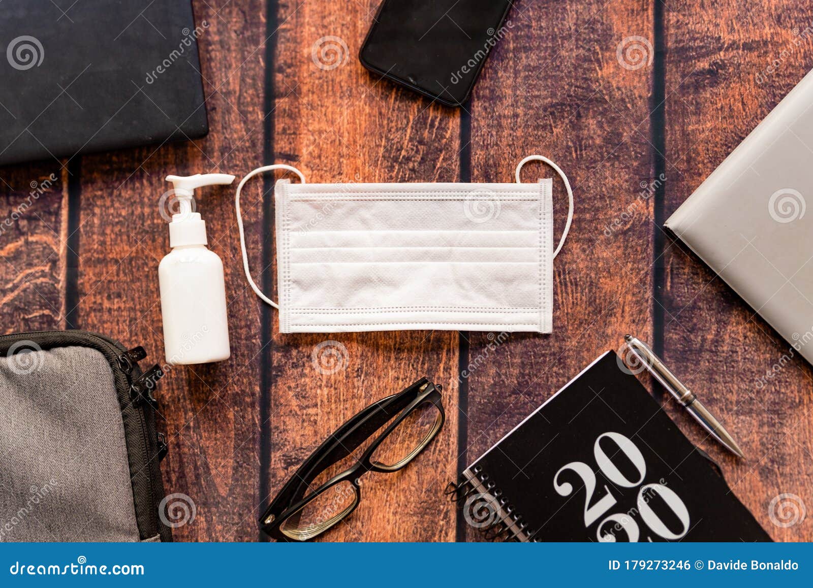 remote work kit on wooden office desk with hand sanitizer and face mask, a solution against the spread of corona virus for