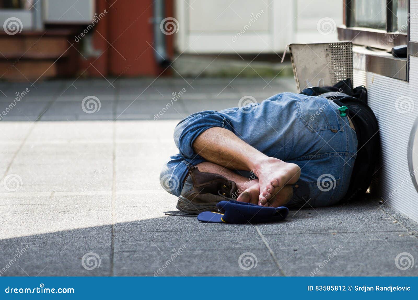 homeless man sleeps on the street, in the shadow