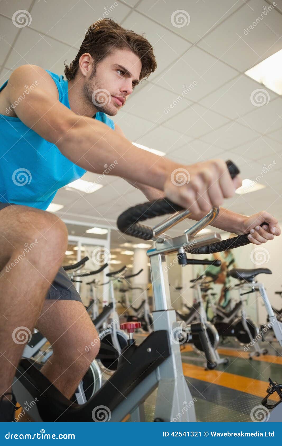 Homem apto focalizado na bicicleta da rotação no gym