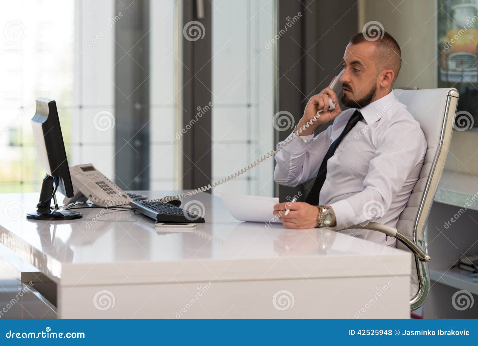 Homem de negócios no telefone. Computador novo de Working At His do homem de negócios ao falar no telefone