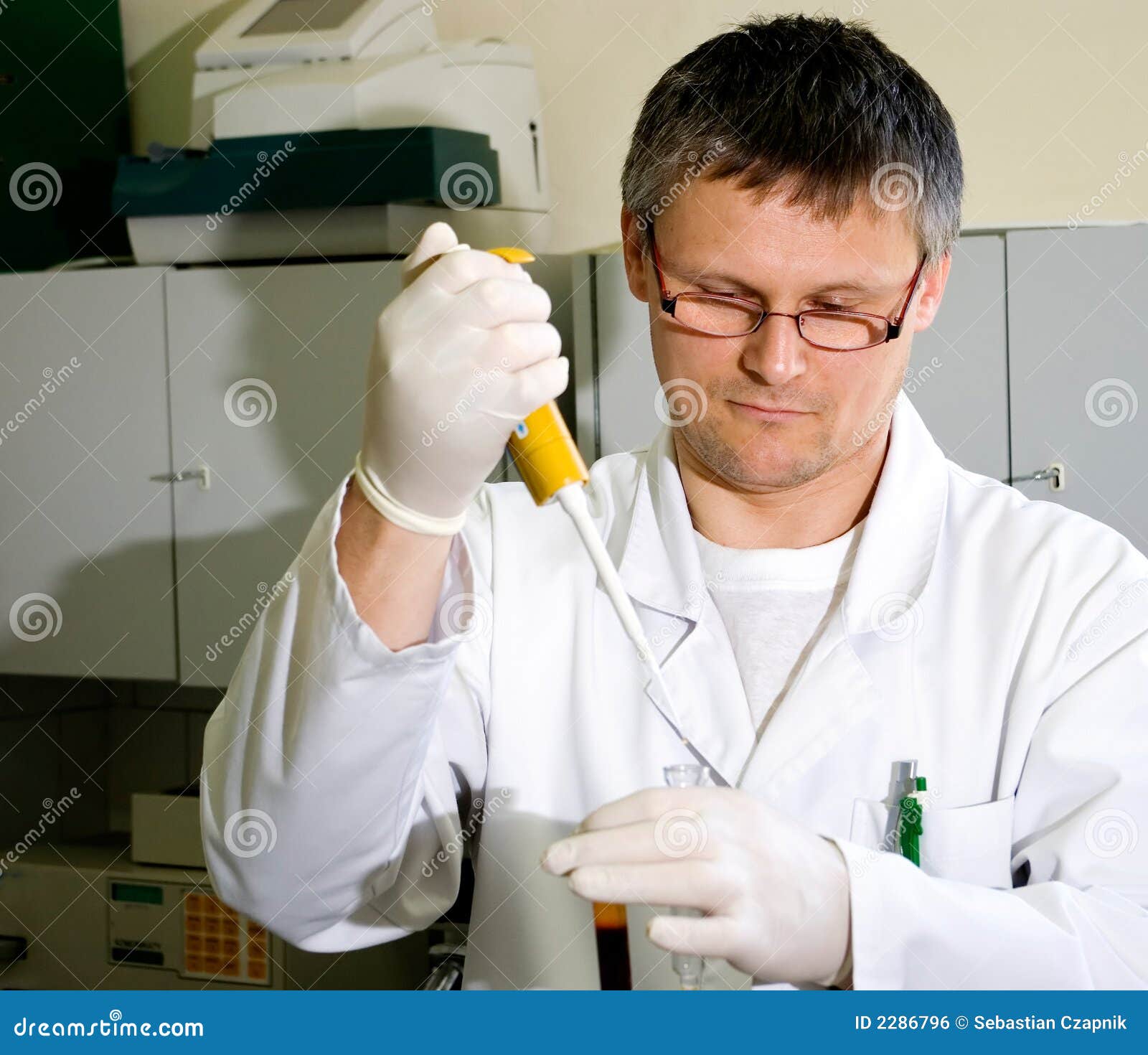 Homem do laboratório. Um homem que trabalha em um laboratório, prendendo algumas câmaras de ar de vidro e <a href="http://www.dreamstime.com/interiors-rcollection5824-resi208938" STYLE="font-size:13px; text-decoration: blink; color:#FF0000"><b>COLEÇÃO de LABORATÓRIO de pipette.MY?</b></a>