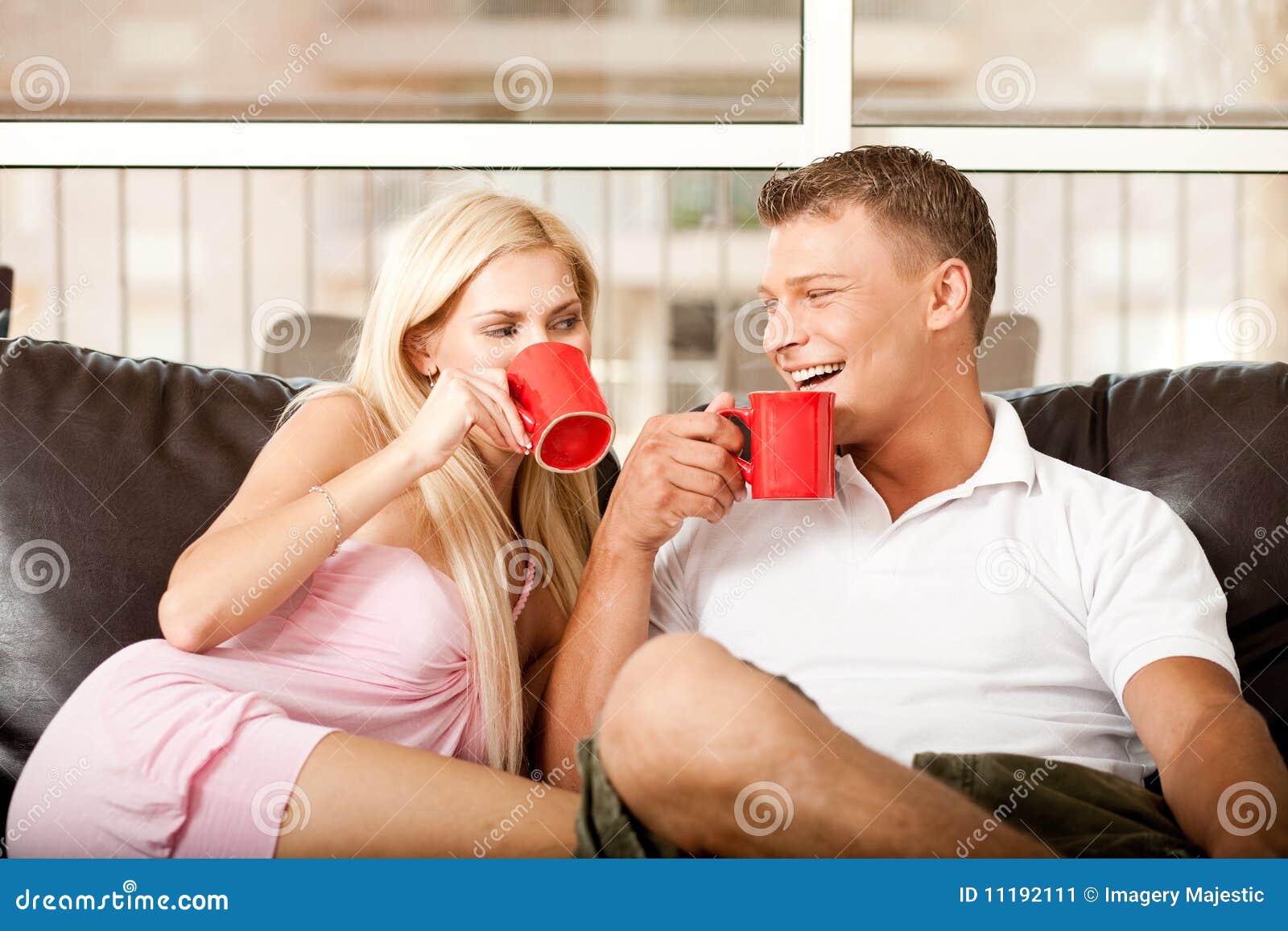 Homem e mulher que apreciam o café. Pares novos que riem ruidosamente como sentam e compartilham do café