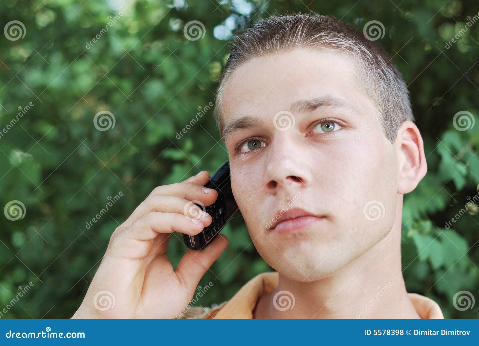 Homem novo no telefone móvel. Adolescente novo que usa ao ar livre seu telefone móvel.