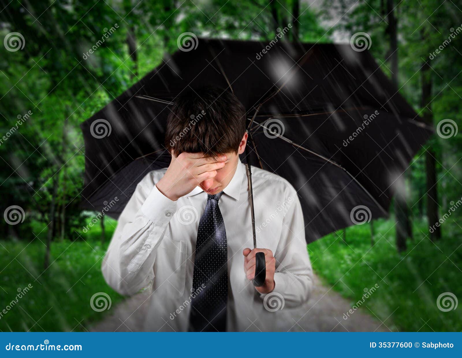 Homem triste sob a chuva. Homem novo triste que anda com o guarda-chuva sob a chuva no parque do verão