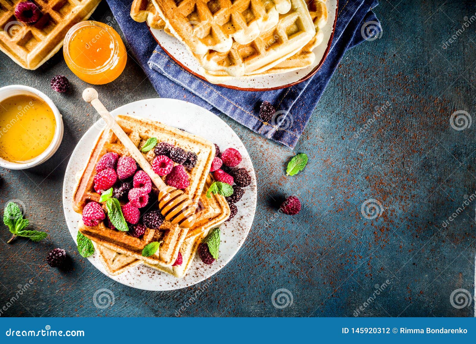 Homemade belgian waffles with berries and honey, on dark blue background copy space