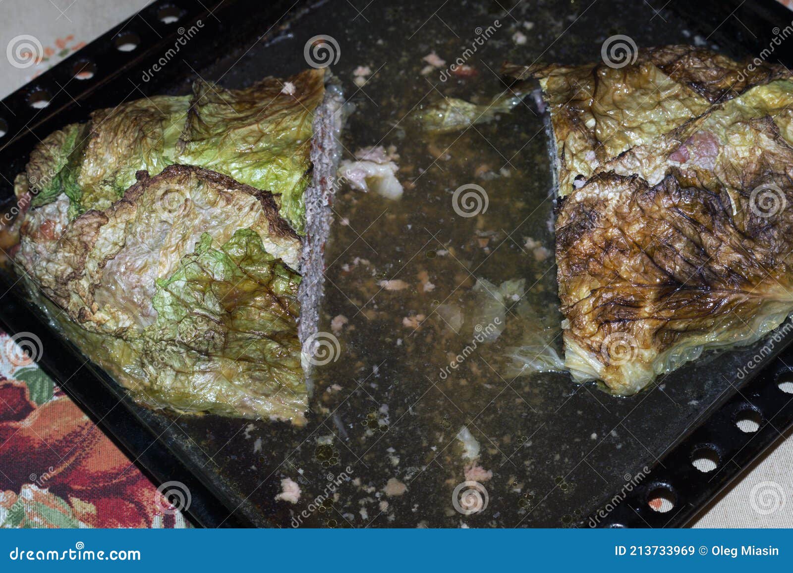 homemade big meat roll in savoy cabbage green blanch leaves, oven-baked in baking tray full of its own juice. cut out pieces from