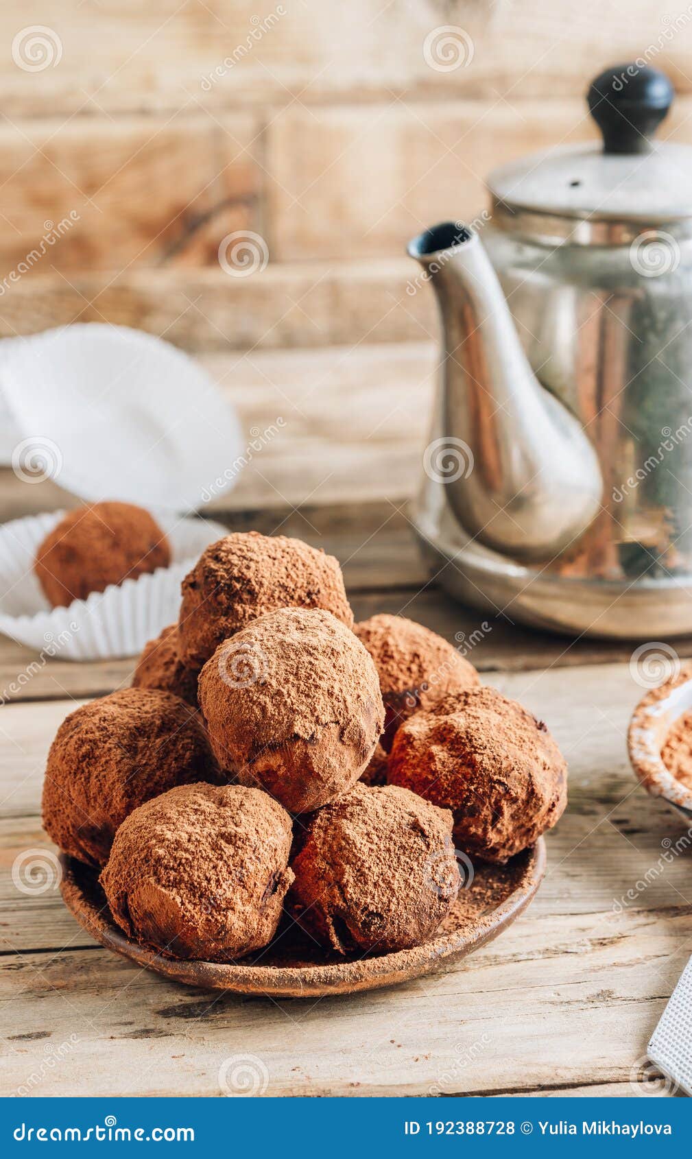 homemade chocolate truffles candy ball on a plate sprinkled with cocoa on a rustc wooden background.