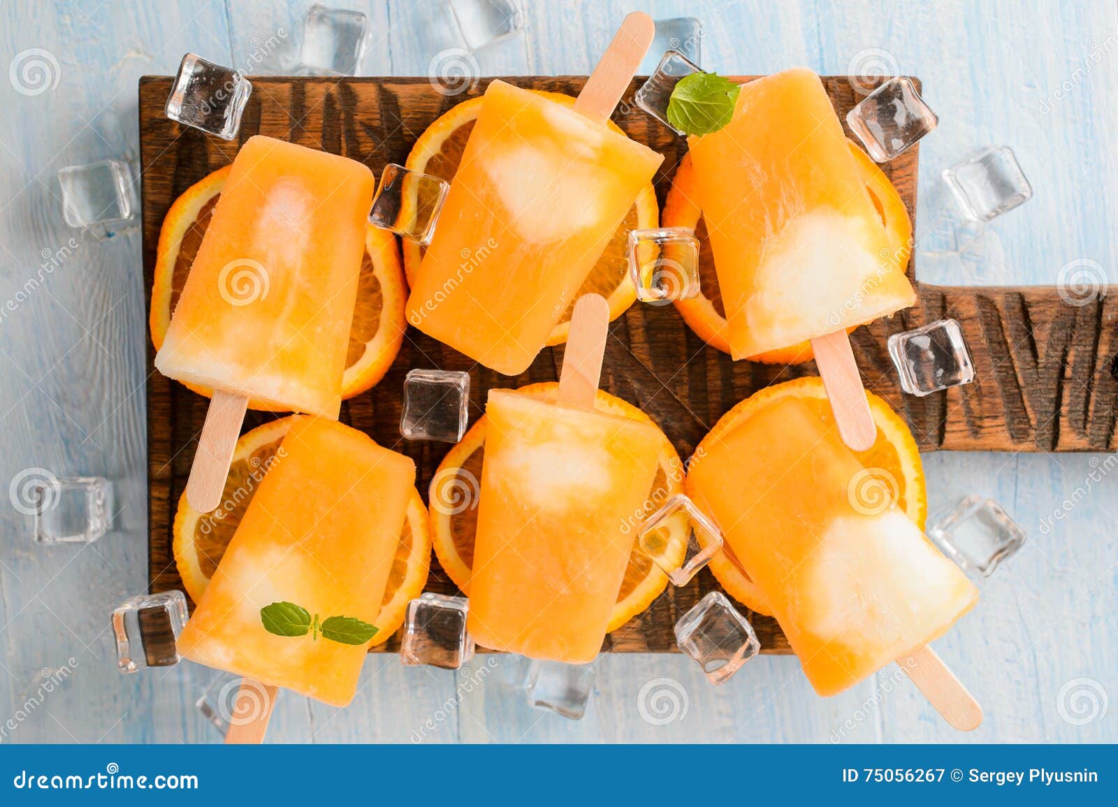 homemade frozen ice cream popsicles made with oragnic fresh oranges on wooden background