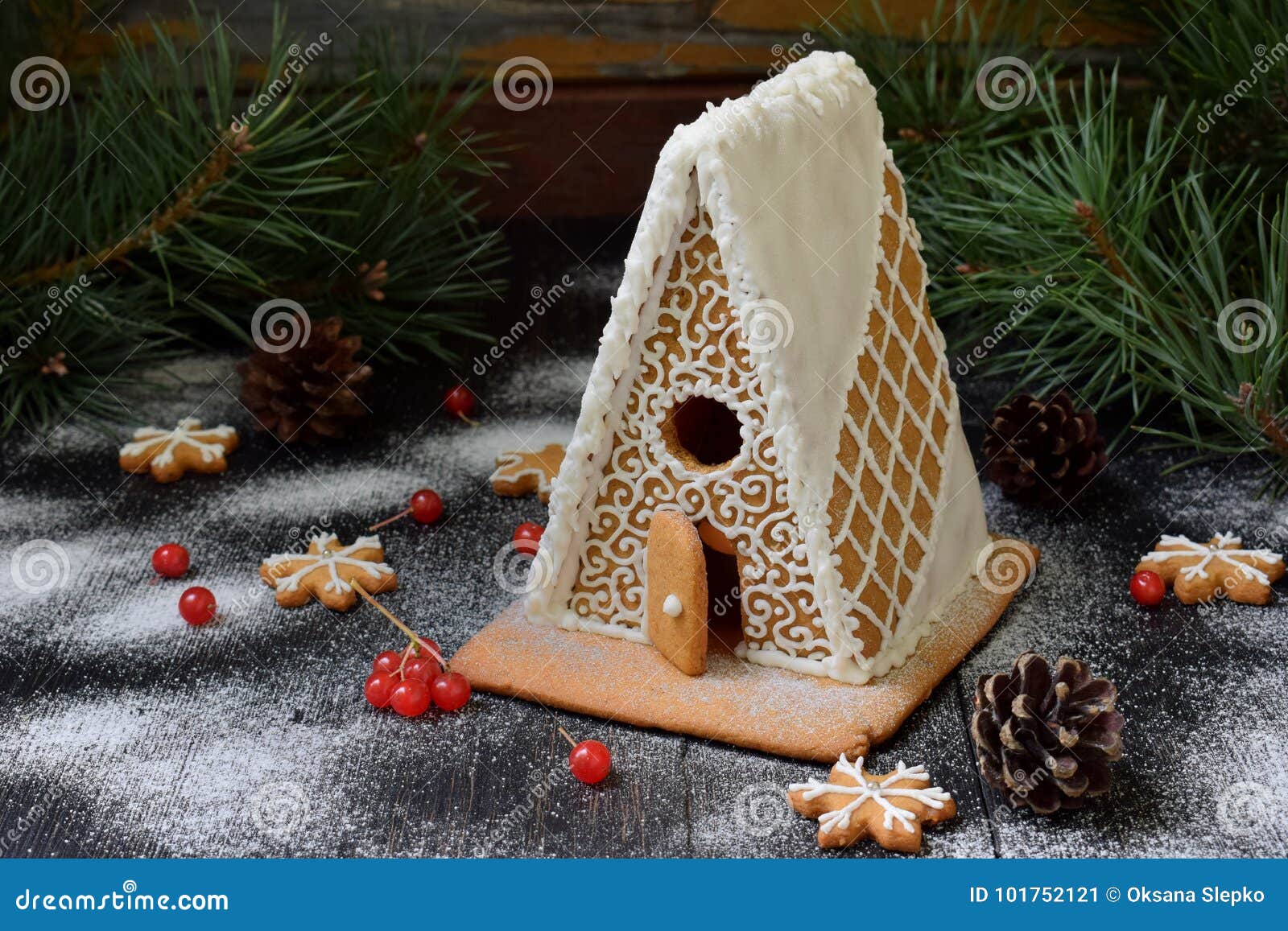 homemade gingerbread house with pine branches, cones and biscuits on dark background. european christmas traditions. xmas holiday