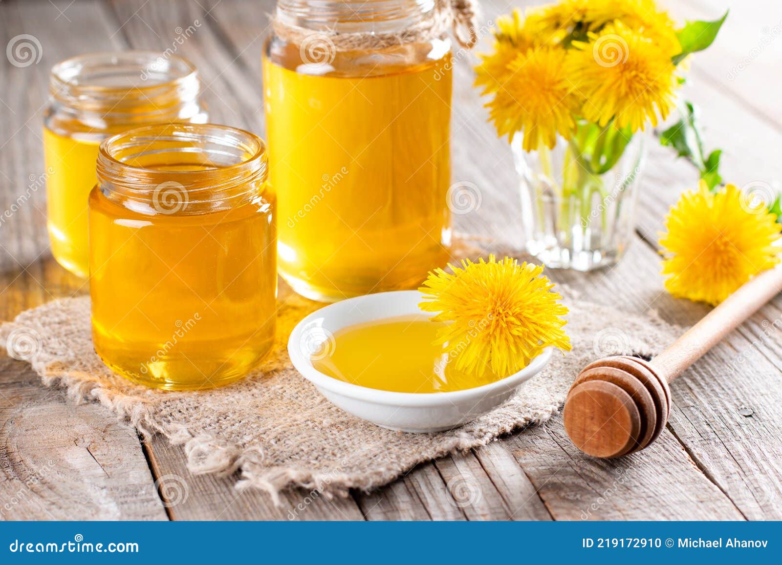 homemade healthy dandelion syrup in a glass bottle, decorated with fresh flowers on wooden background