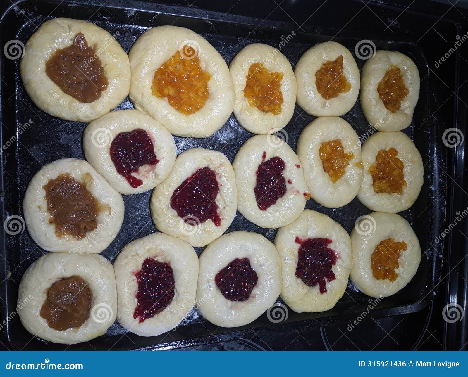 homemade jam filled raw kolachi pastry proofing on a baking pan