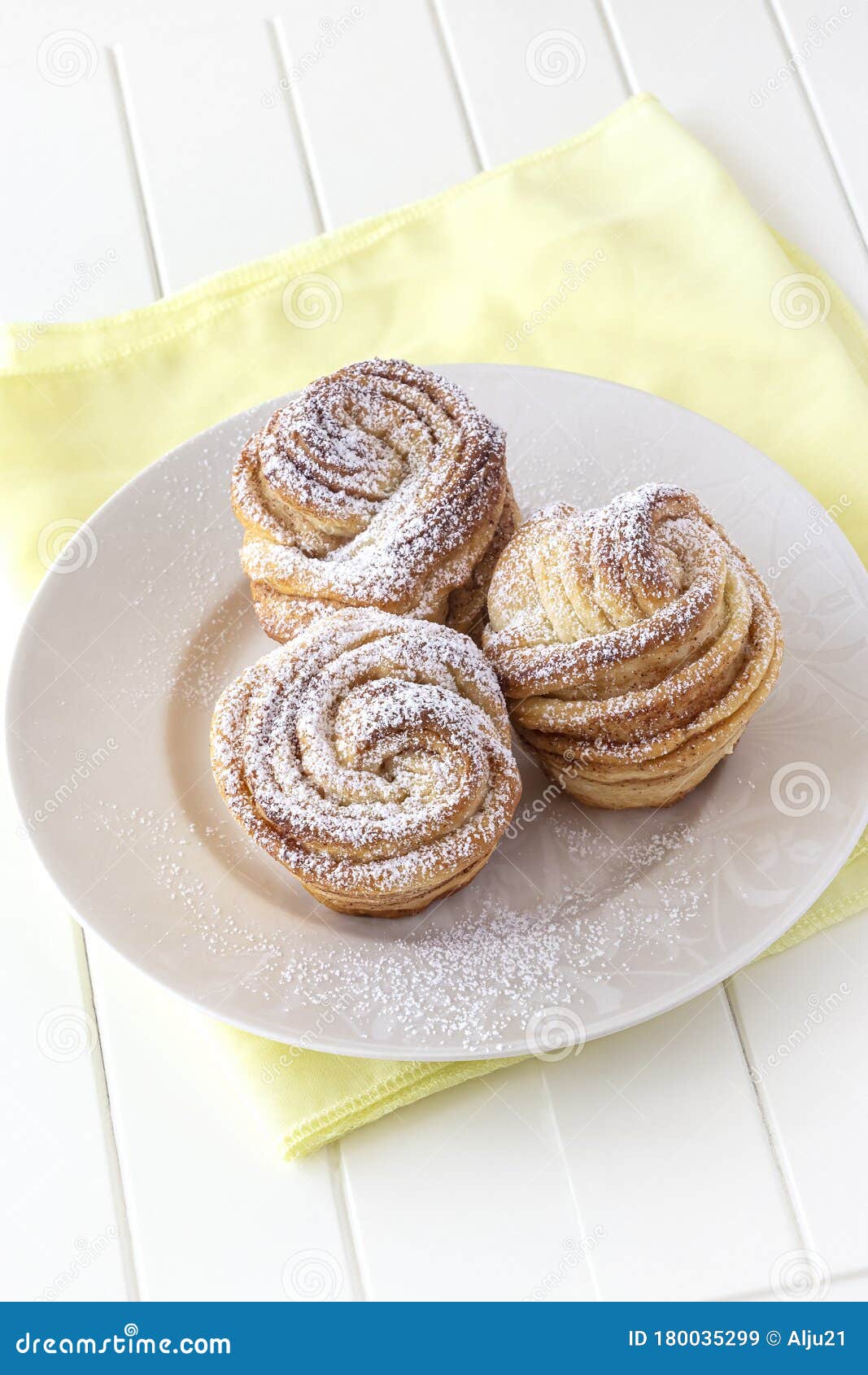 homemade modern cruffin cake, yeast rolled cinnamon bun sprinkled powdered sugar. copy space. white background