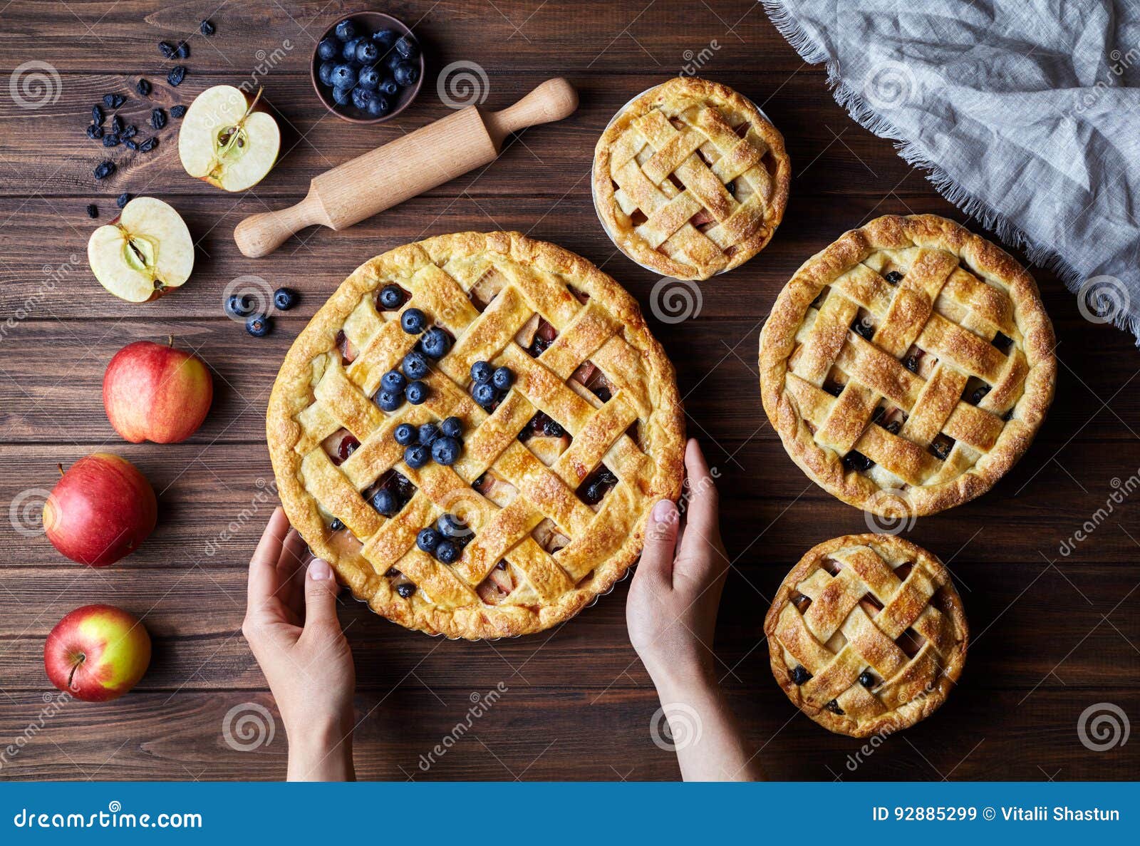 homemade organic apple pies bakery products hold female hands on dark wooden kitchen table with raising, bluberry