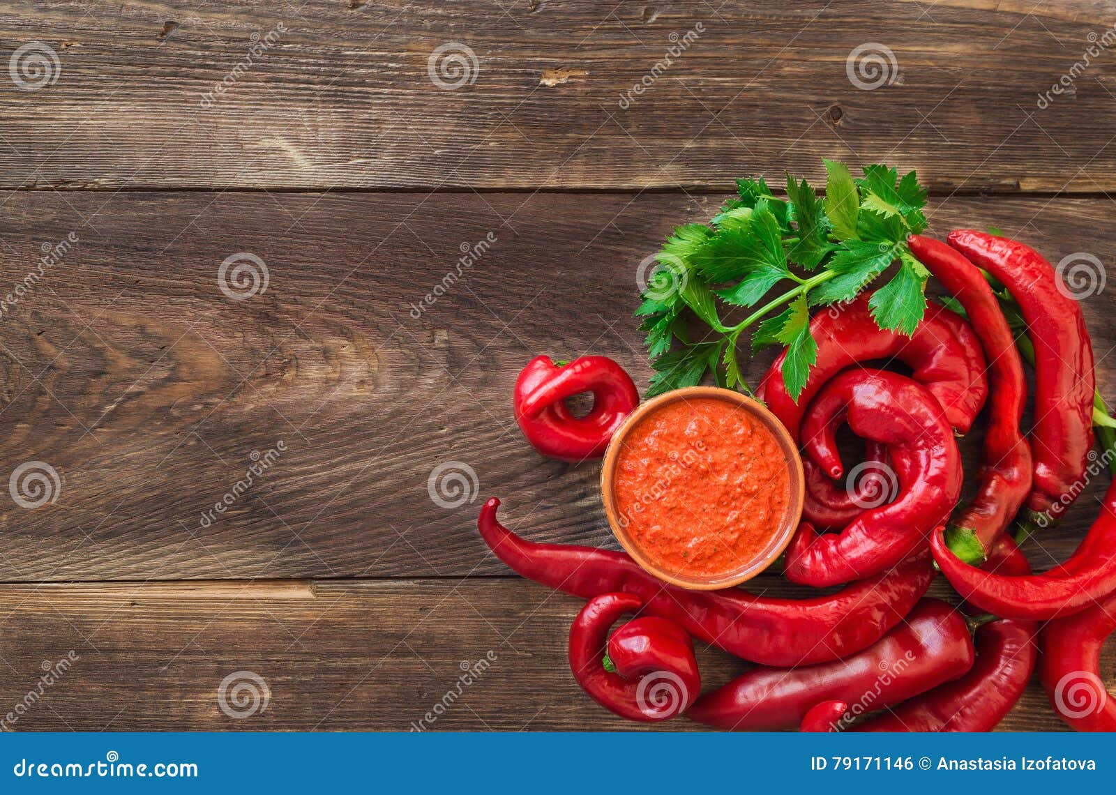 Homemade sauce and red hot chili peppers and celery on rustic wooden background. Top view.