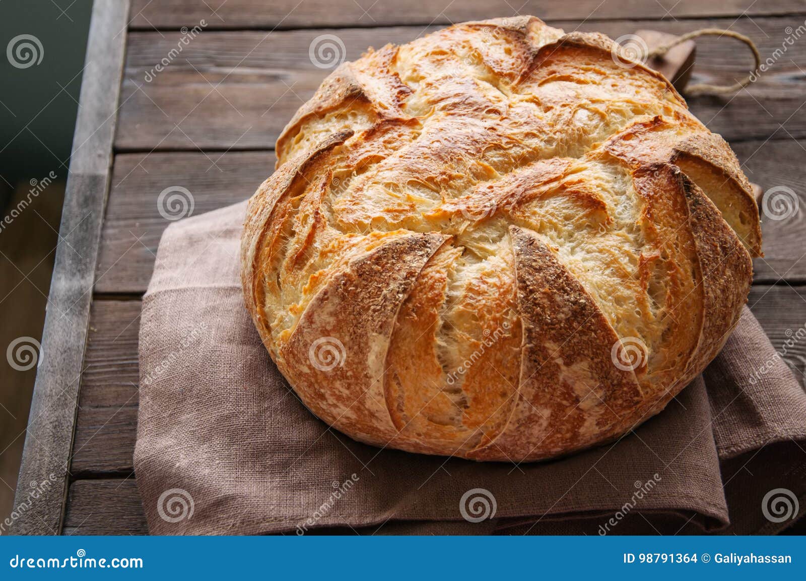 homemade sourdough bread in a wooden tray on a wooden background