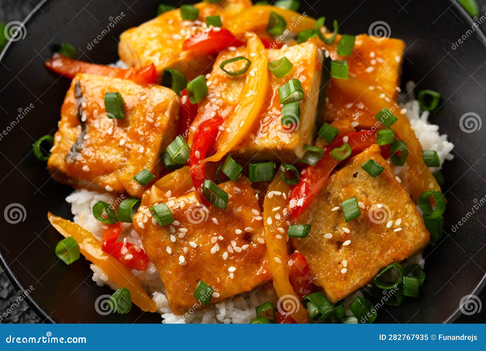 Homemade Stir Fry Tofu with Vegetables and Rice in Black Bowl. Stock