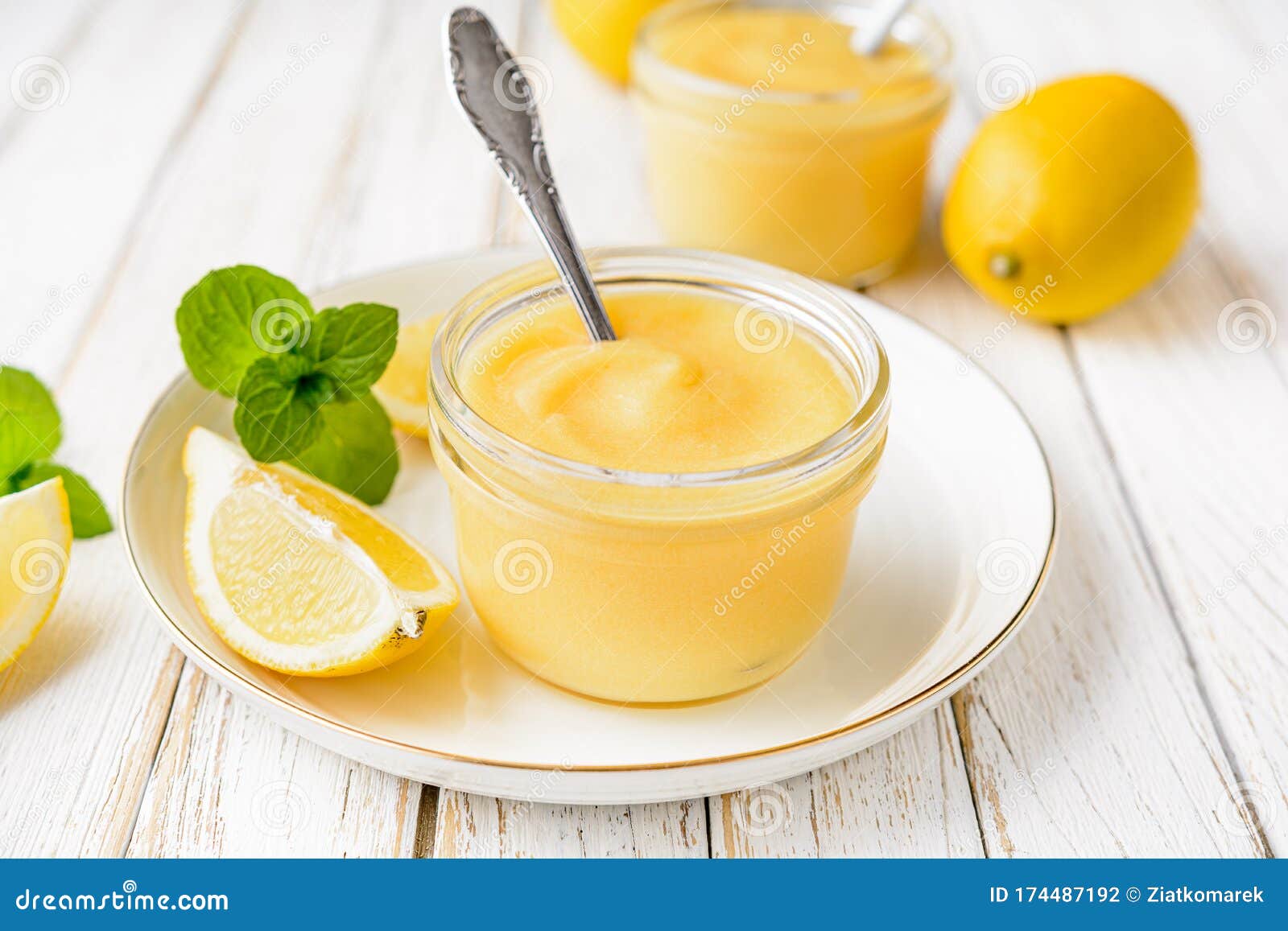 homemade tangy lemon curd decorated with fresh fruit in a glass jars on rustic wooden background