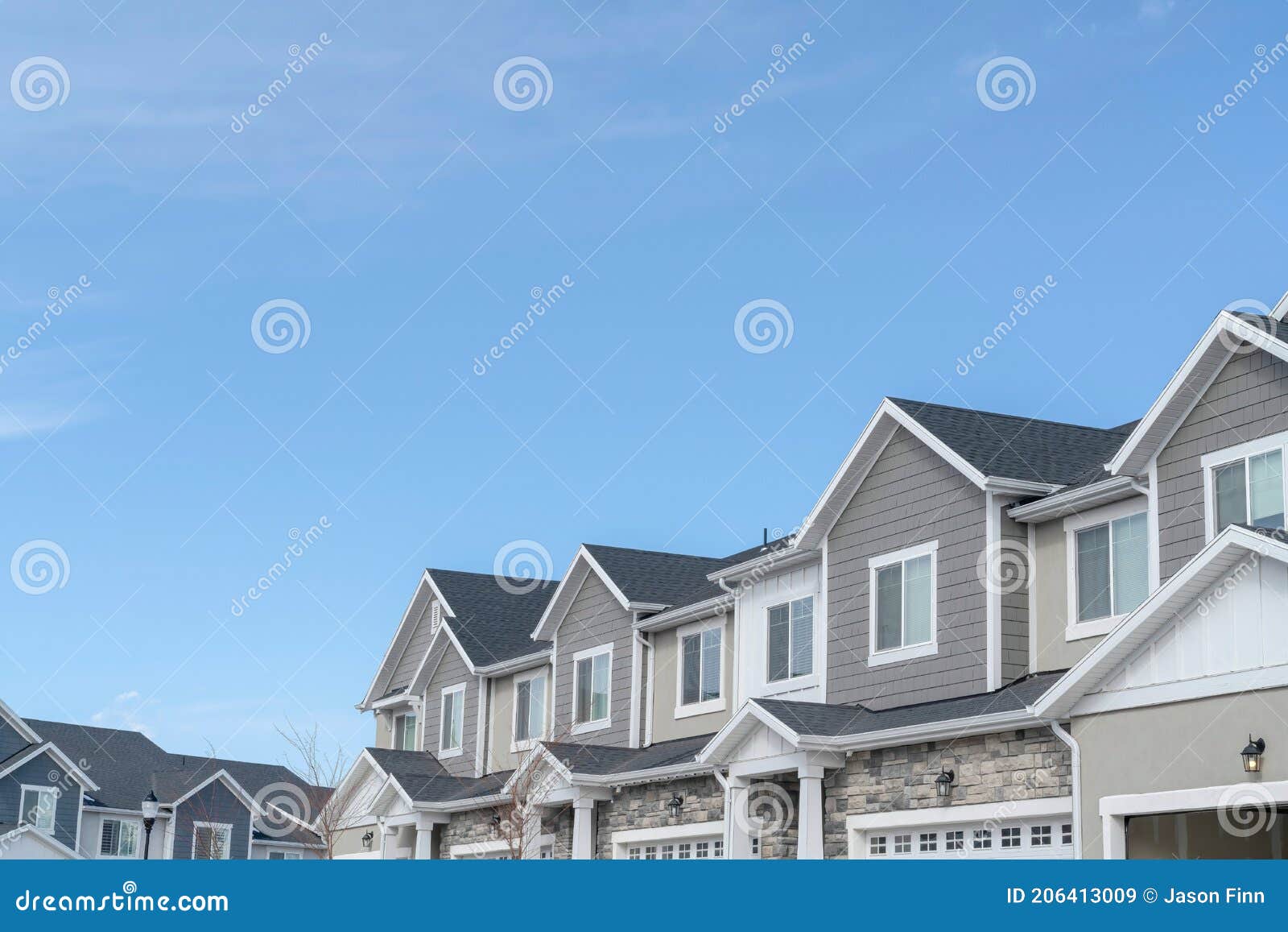 homes with gable roofs and gray exterior walls against blue sky in the suburbs