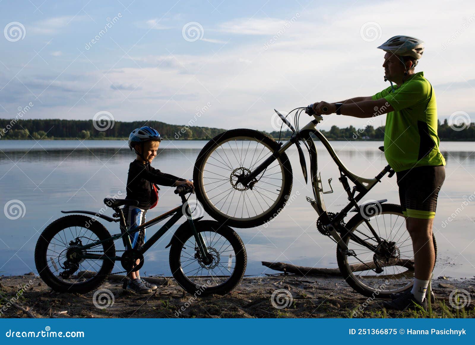 Homme Adulte Et Un Garçon Avec Deux Vélos En Casques Près Du Lac