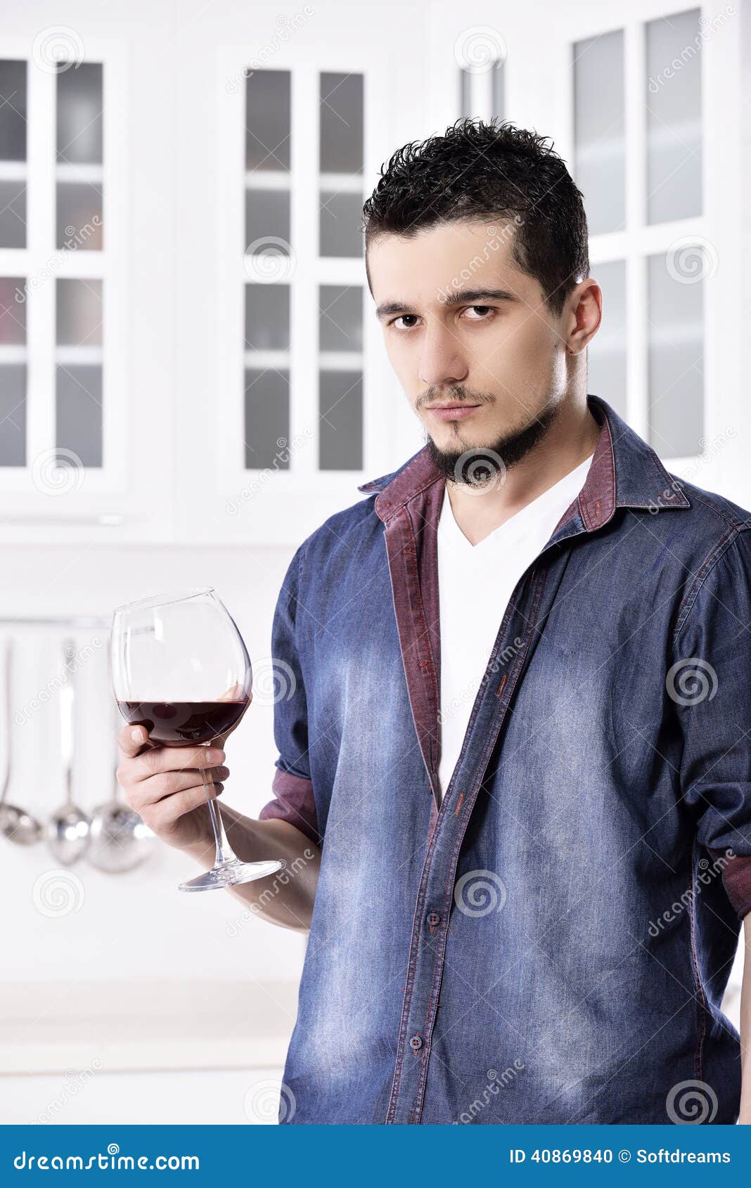 Homme de regard bon heureux rêveur buvant du vin rouge dans la cuisine