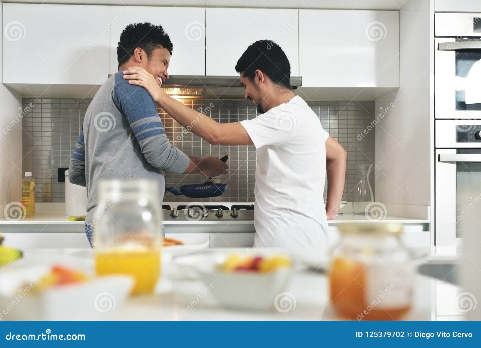 Homosexual Couple Eating Breakfast Cooking in Kitchen Stock Photo