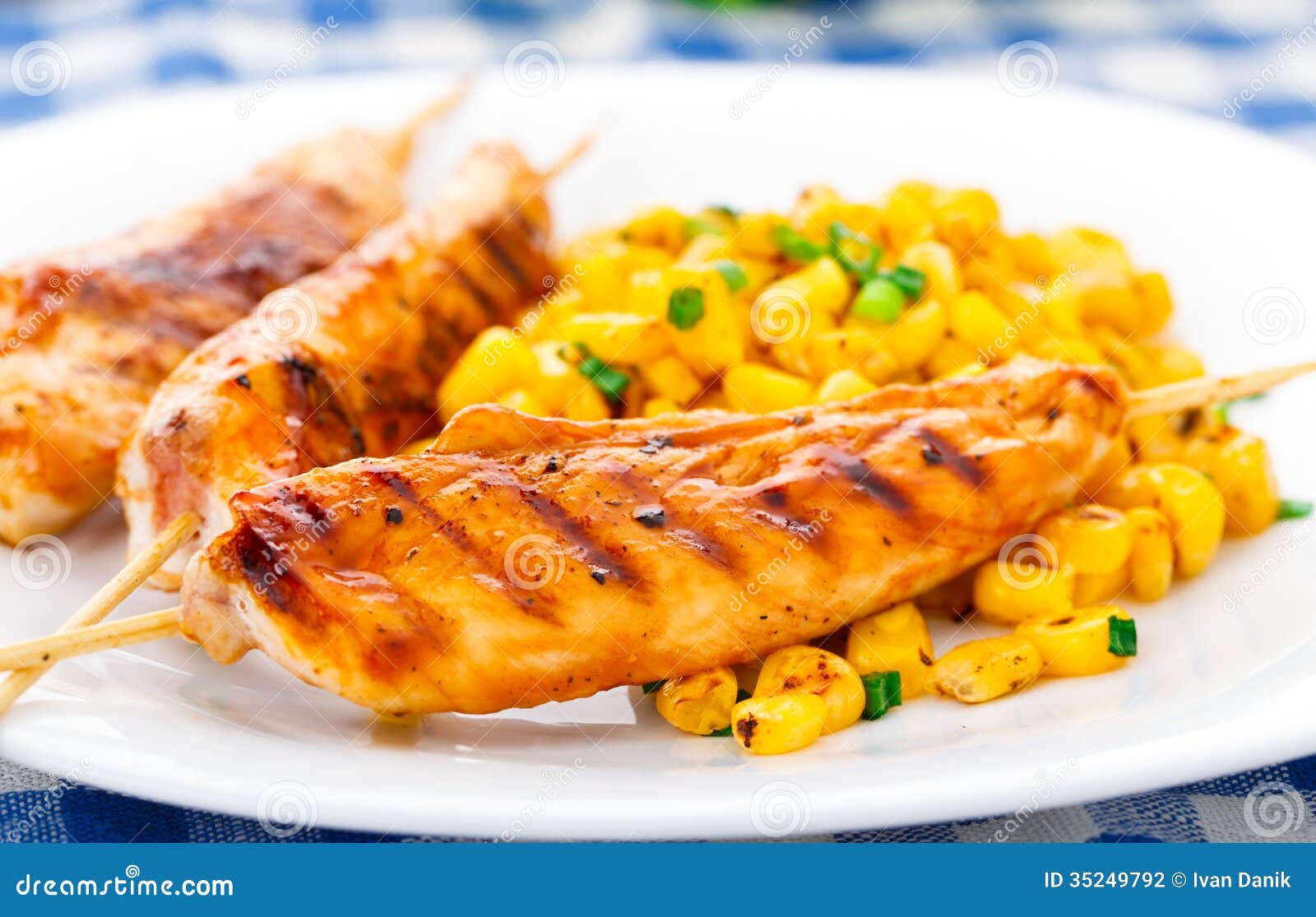 Honey chicken skewers with grilled corn salad on a plate