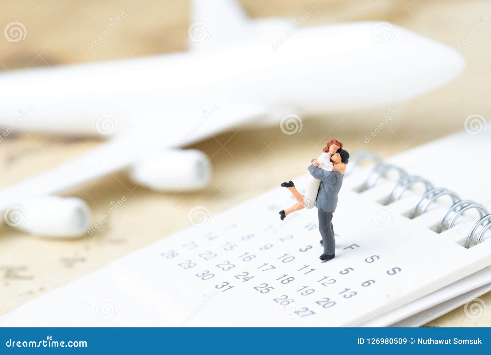 honeymoon trip, wedding proposal, family travel tourism and vacation concept, miniature young couple standing on calendar with to