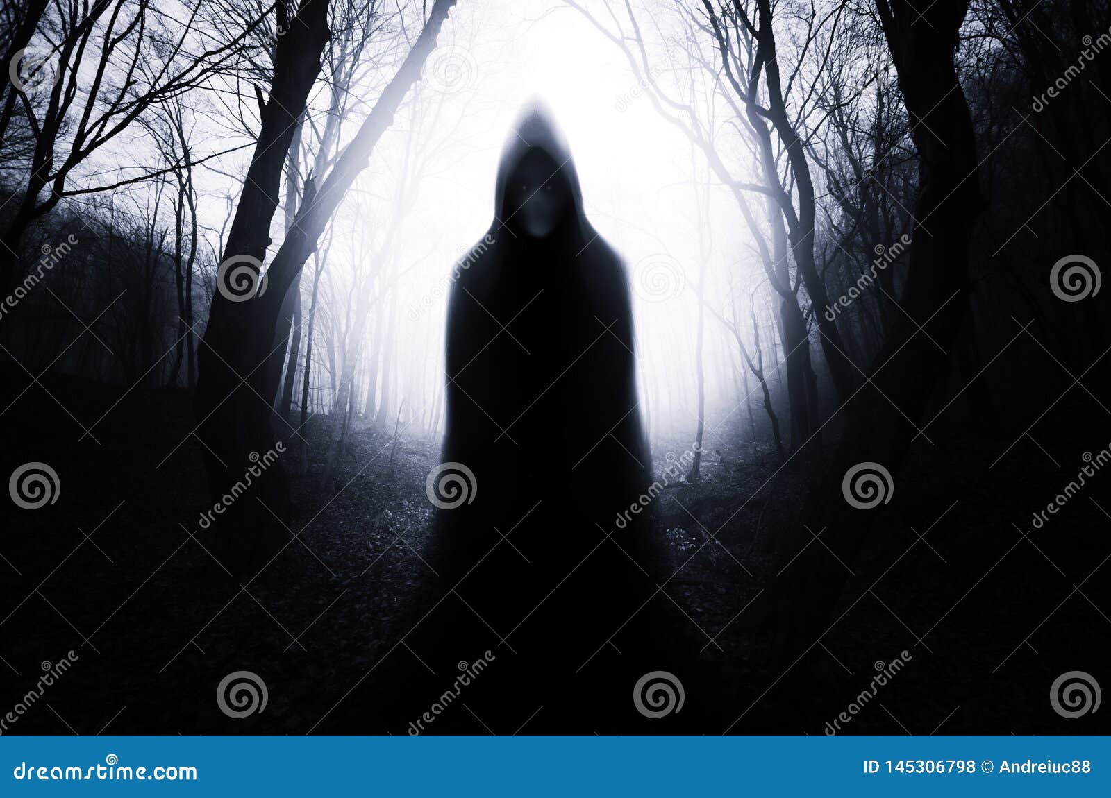 hooded ghost in haunted forest with fog on halloween night