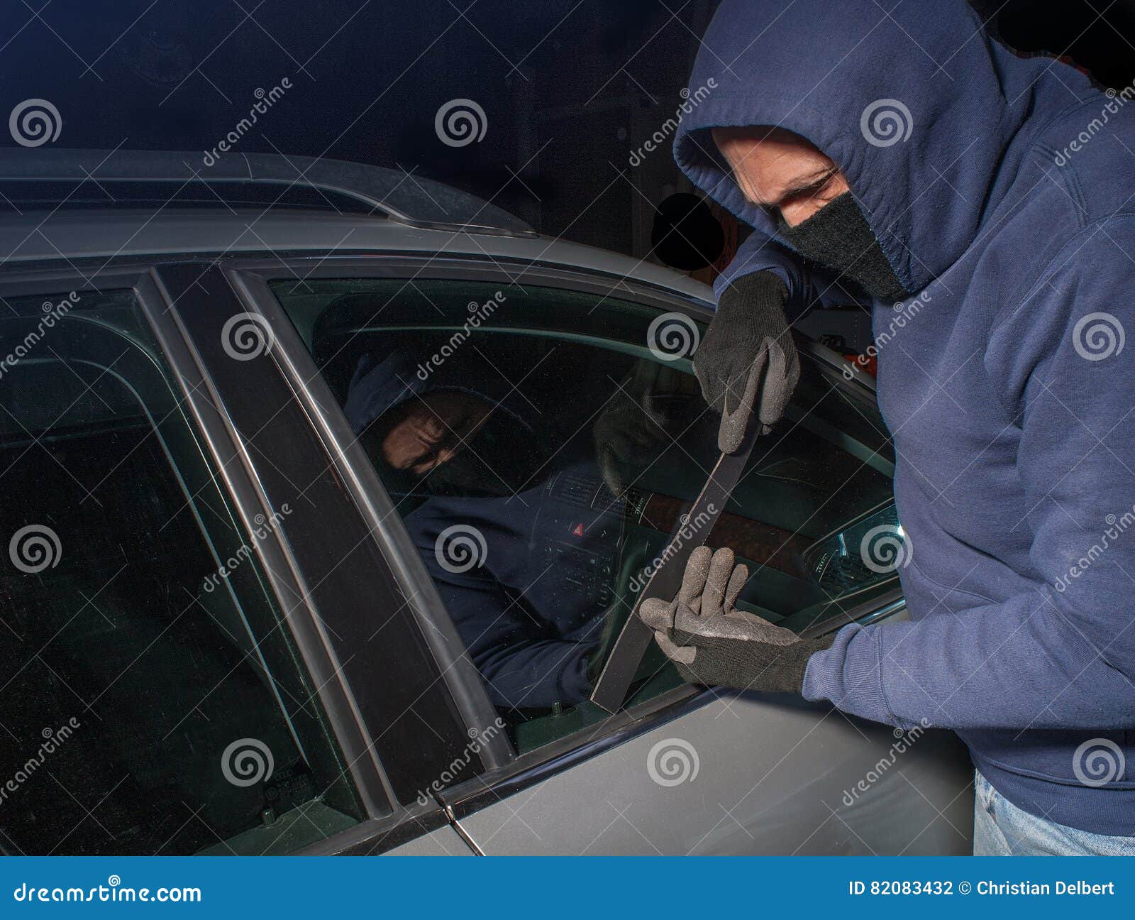 hooded thief looking to break into a car