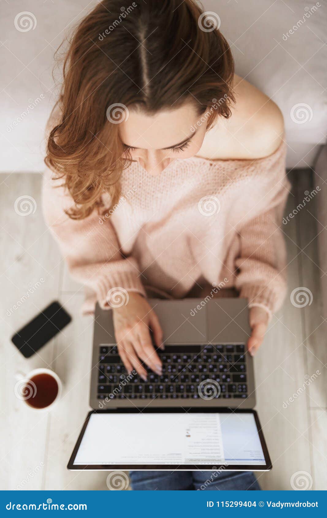 Hoogste mening van een vrouw die aan laptop computer werken terwijl het leunen op een bank