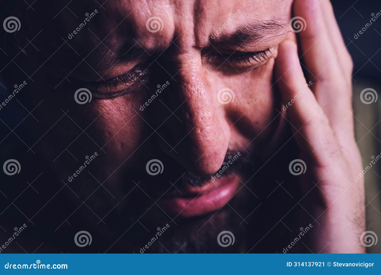 hopelessness and despair, closeup of portrait of sad crying adult man grieving in dark room