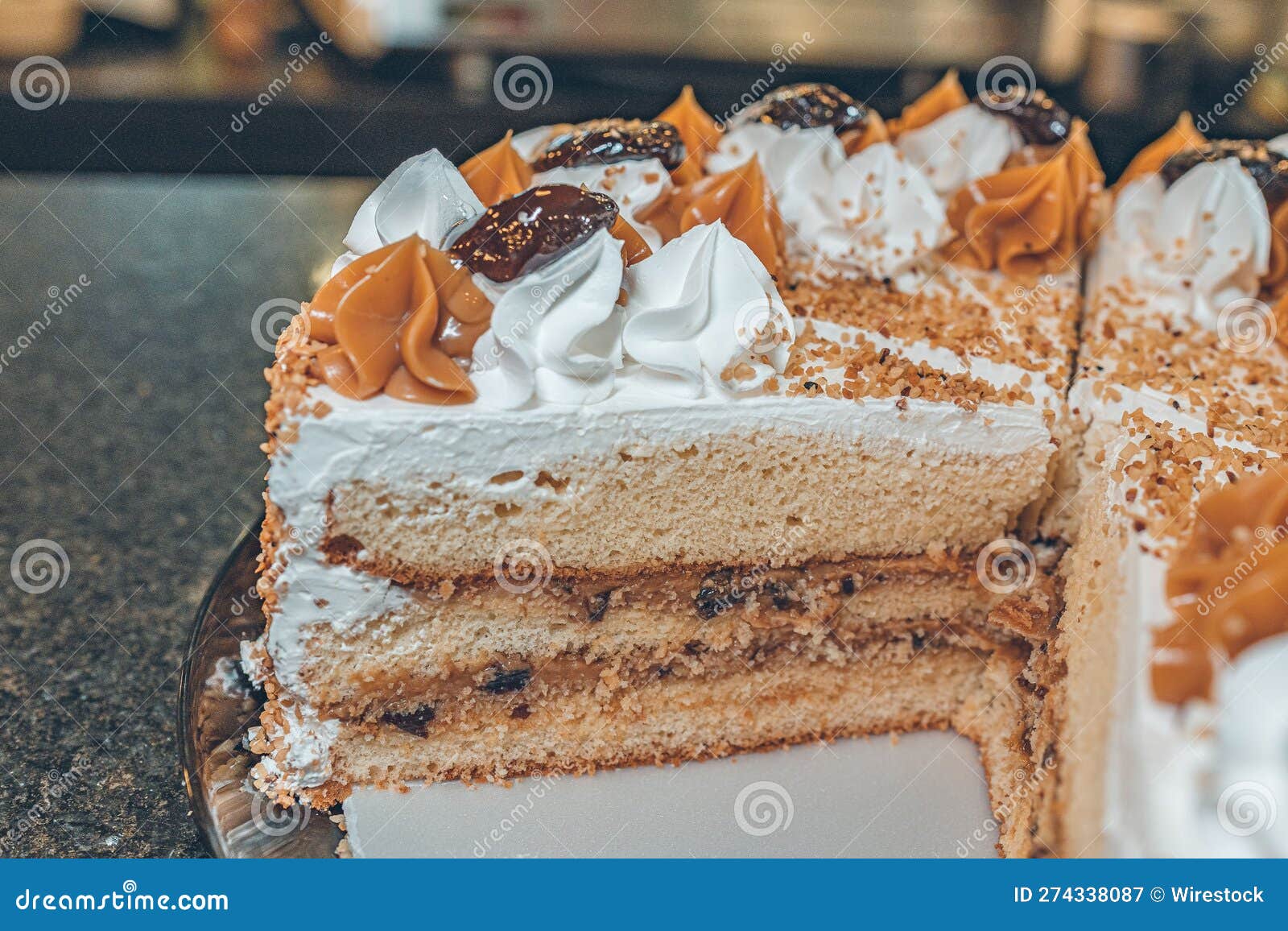 horizontal photo of a biscuit cake with cream, cherry and caramelo sauce