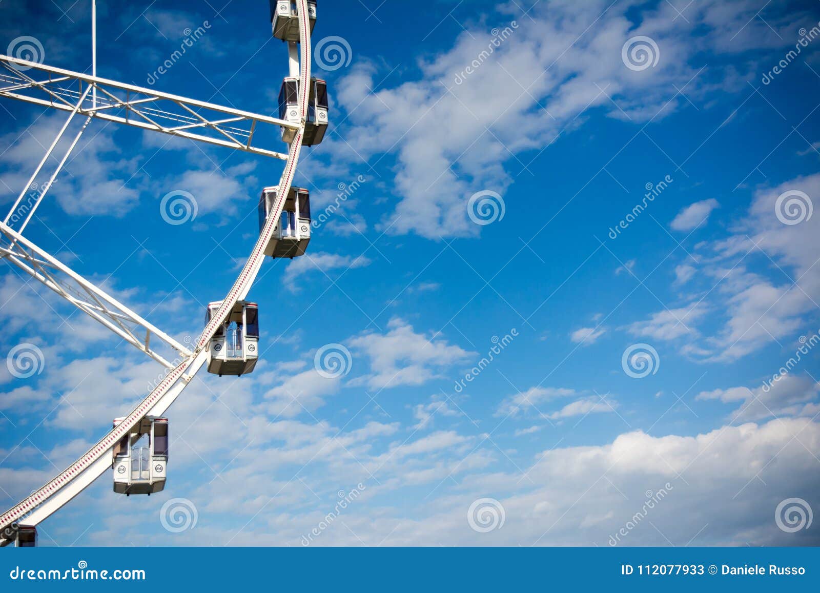 Horizontal View of a White Ferris Wheel on Partially Cloudy Sky Stock