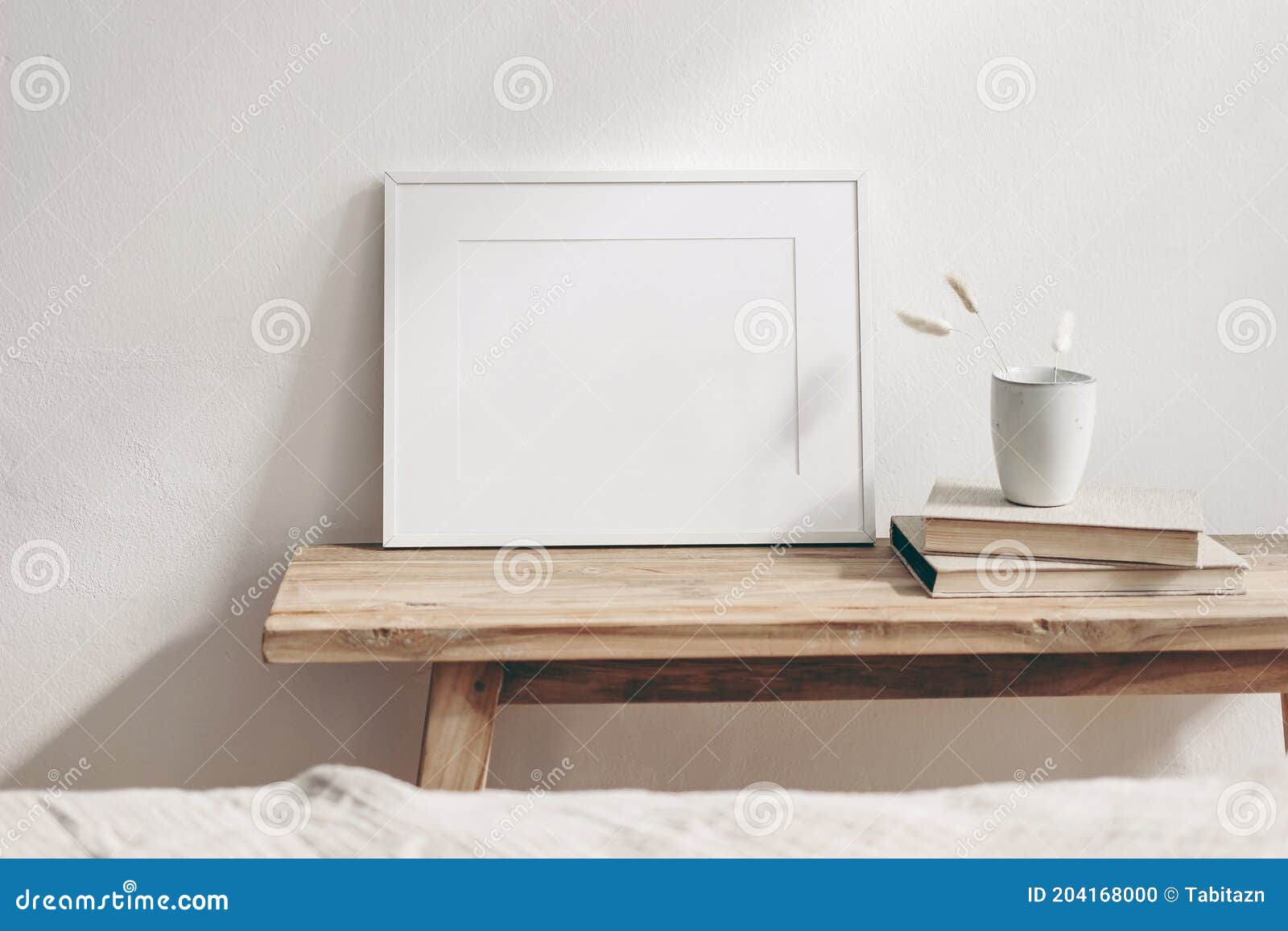 horizontal white frame mockup on vintage wooden bench, table. ceramic mug with dry lagurus ovatus grass and books. white