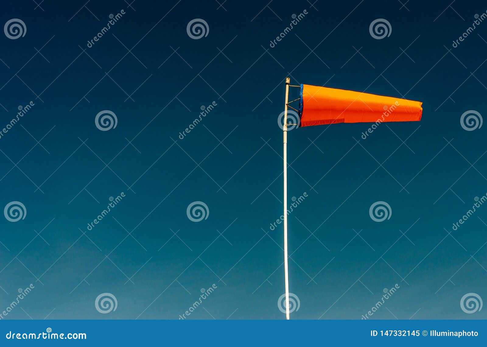 Horizontally Flying Orange Windsock and Clear Dark Blue Sky. Stock